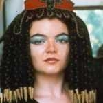 Modella indossa una parrucca egizia nobile in lana nera e marrone con accessori dorati.