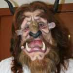 Uomo che indossa una maschera con denti e corna la bestia della favola: la bella e la bestia.
