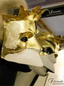 immagine di un manichino che indossa la maschera detta larva o bauta, tipica di venezia, maschera neutra, non espressiva, ma in questo caso dipinta d'oro